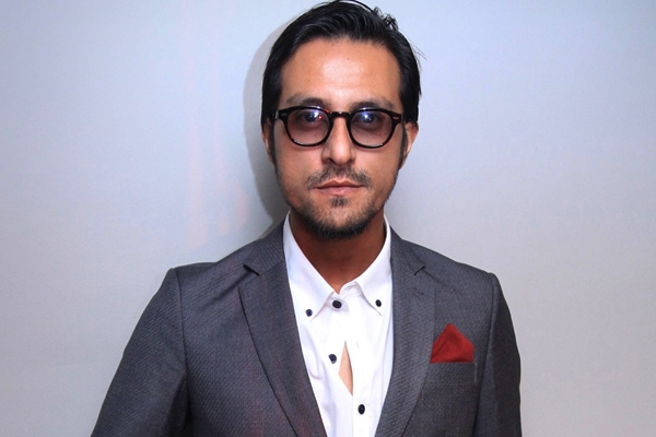 Bront Palarae sebagai Rahman, pengulas sukan yang mengulas perlawanan bola sepak dalam Ola Bola.